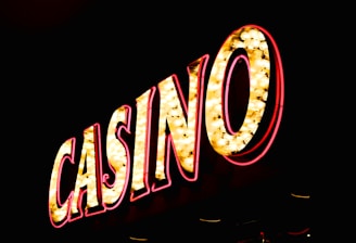 Brightly illuminated letters spell out 'CASINO' with glowing yellow bulbs and red outlines against a dark background.