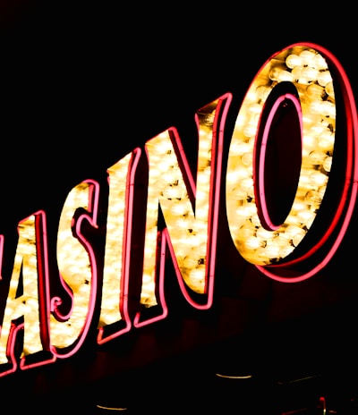 Brightly illuminated letters spell out 'CASINO' with glowing yellow bulbs and red outlines against a dark background.